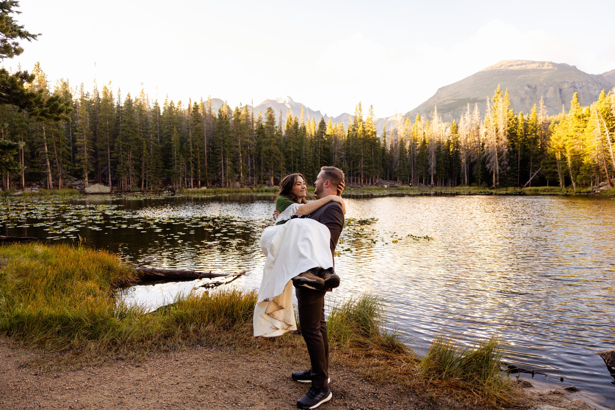 bride and groom by Dream Lake for their elopement, groom holding his bride in his arms. 