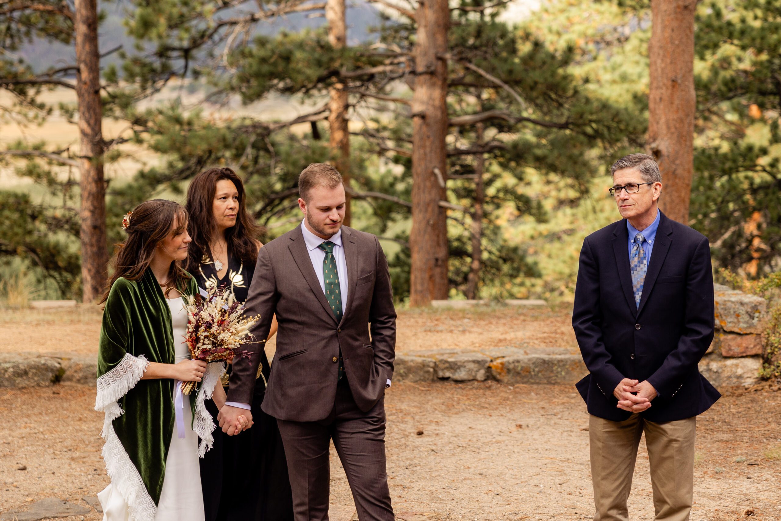 a guest says a prayer while bride and groom listen before their Dream Lake elopement ceremony. 
