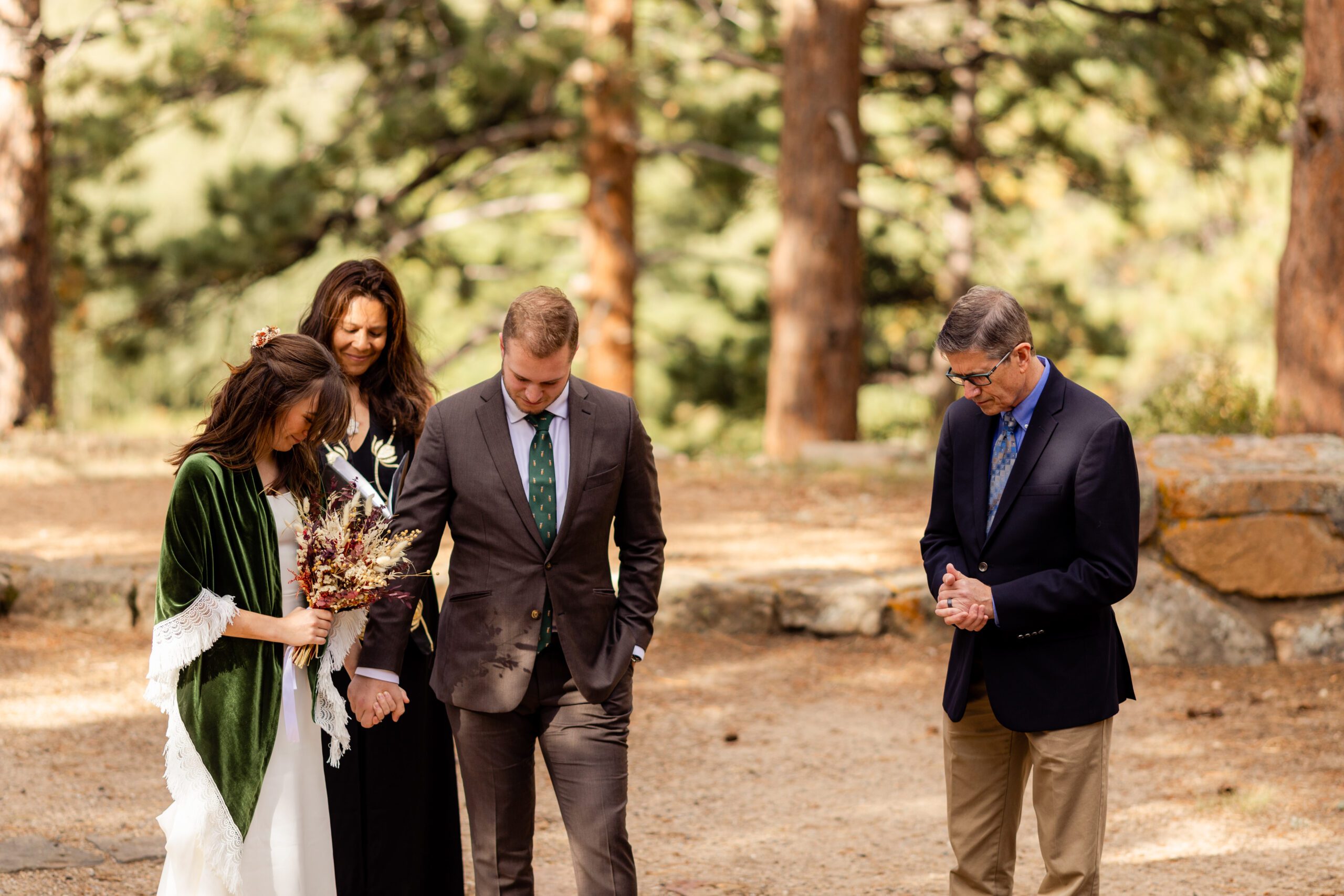 bride and groom and officiant bow their heads in prayer at their Dream Lake elopement.