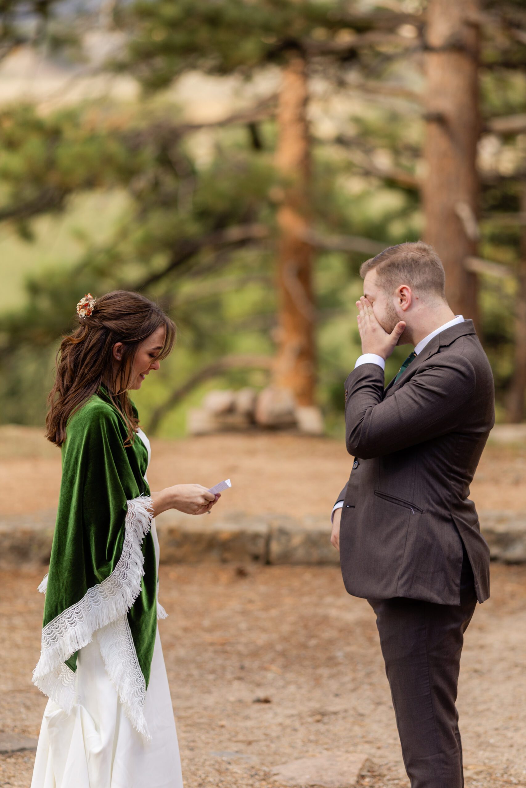 groom reads her vows to the groom who is wiping a tear from his eye at their Dream Lake elopement.