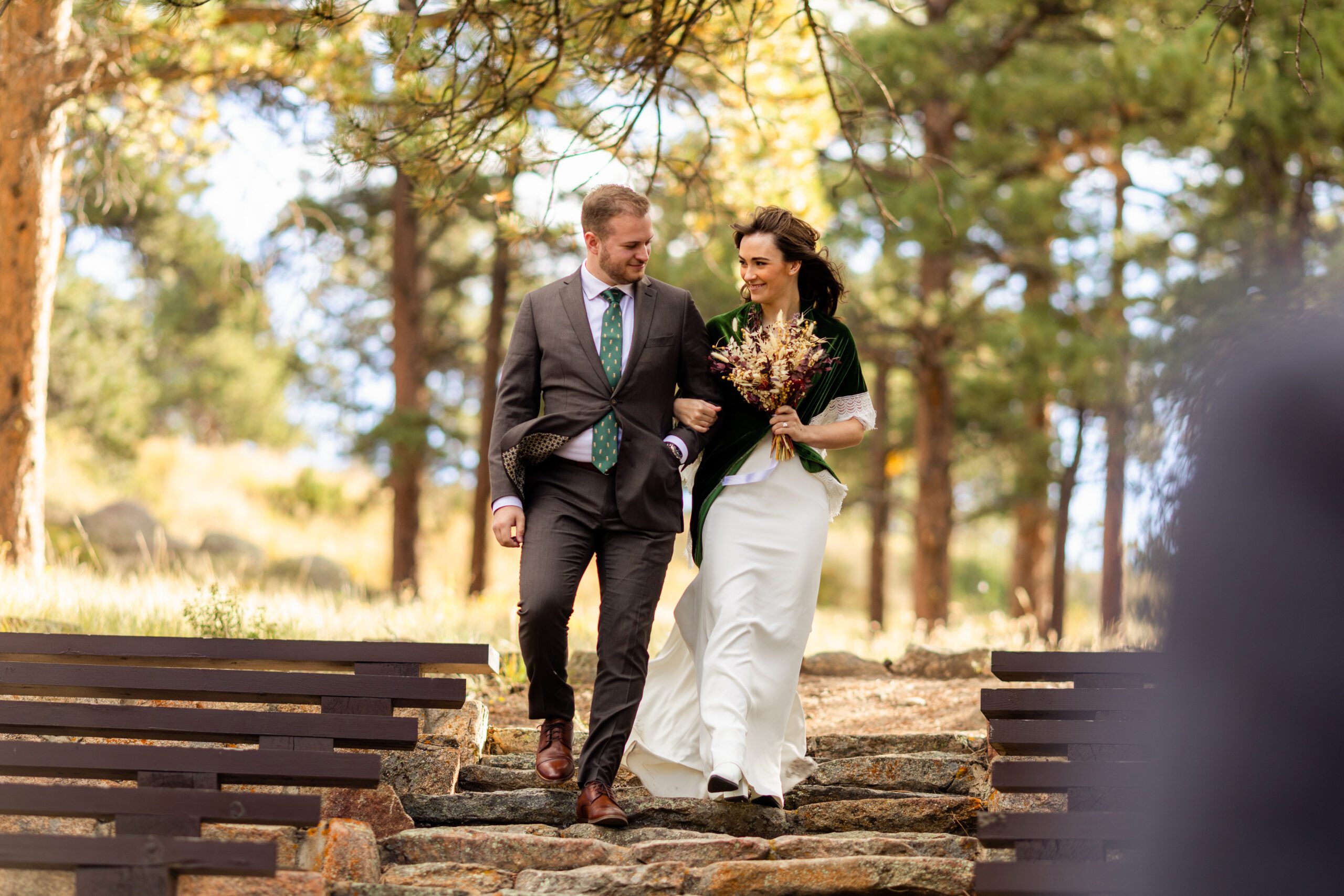 bride and groom look sweetly  at each  other while walking down the aisle at their Dream Lake elopement.