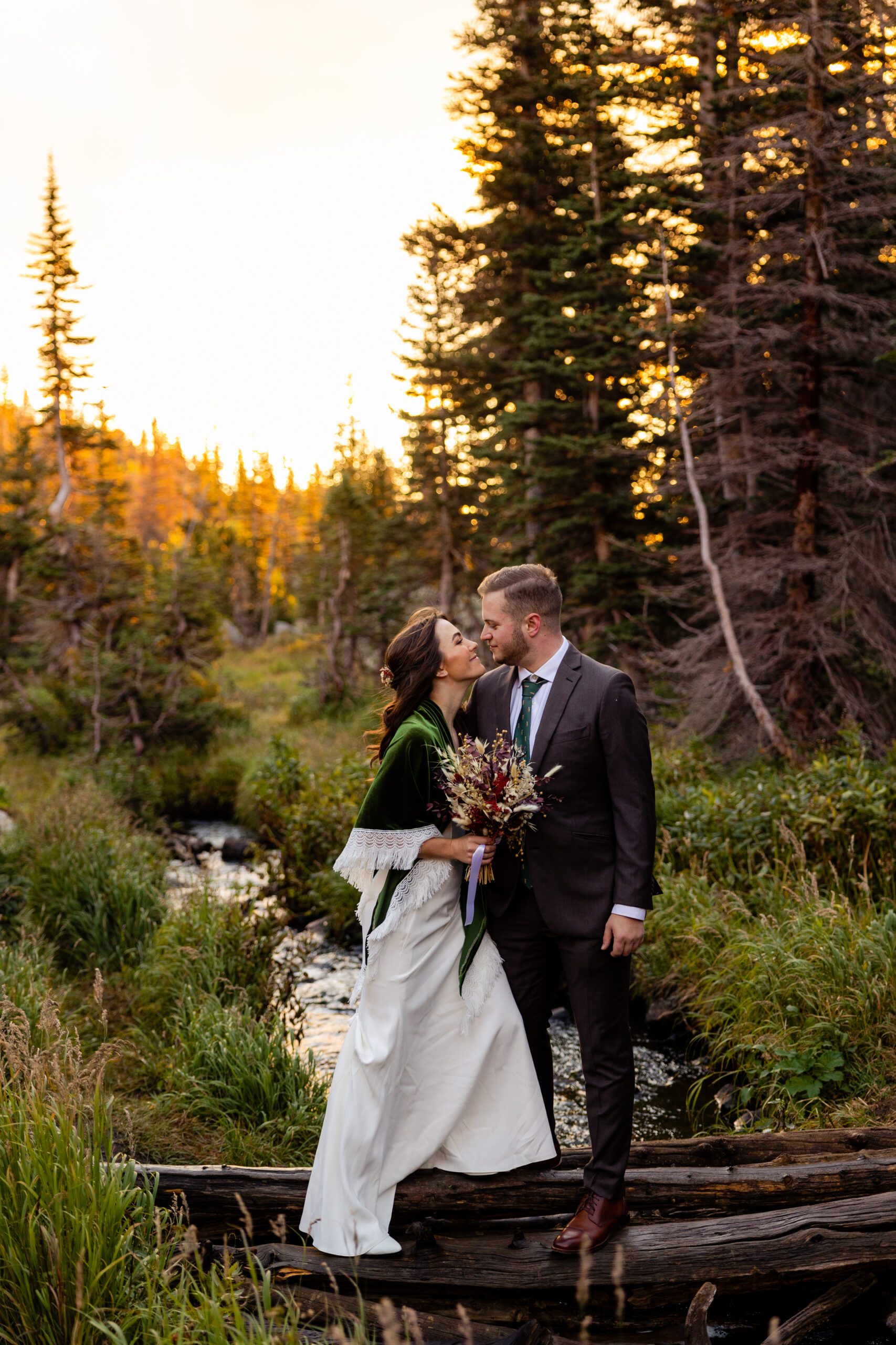 bride and groom standing over a river on their Dream Lake elopement day. 