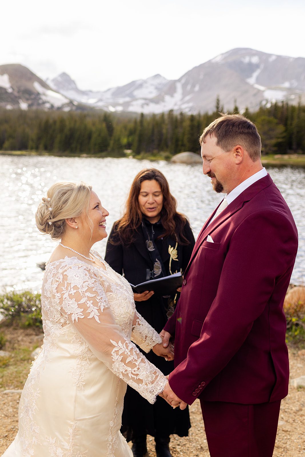 bride and groom holding hands and smiling at each other during their Brainard Lake wedding ceremony.