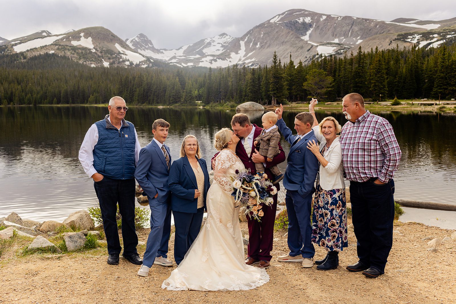 bride and groom kissing with their families at Brainard Lake.