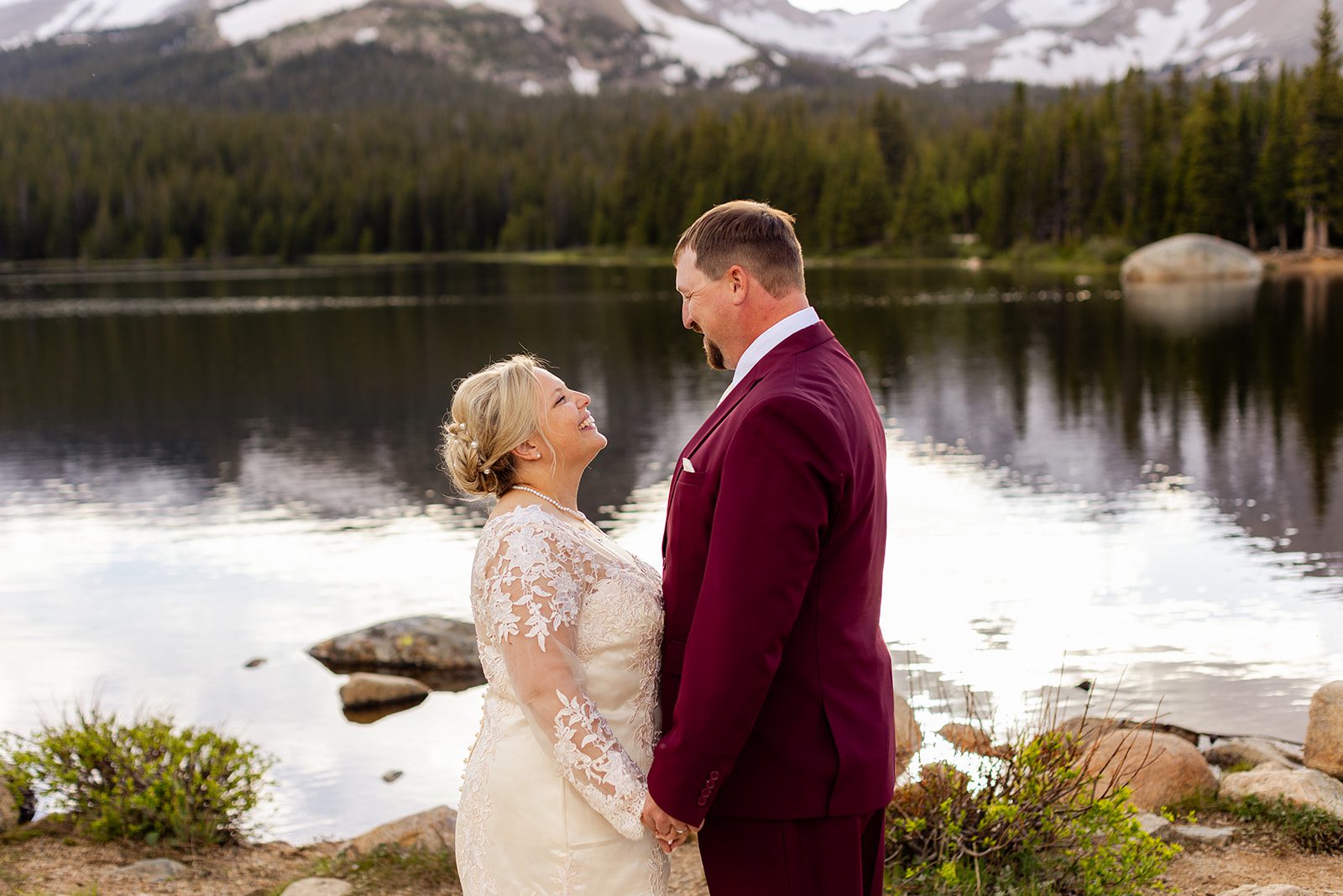 Bride and groom smiling at each other with Brainard Lake in the backdrop.