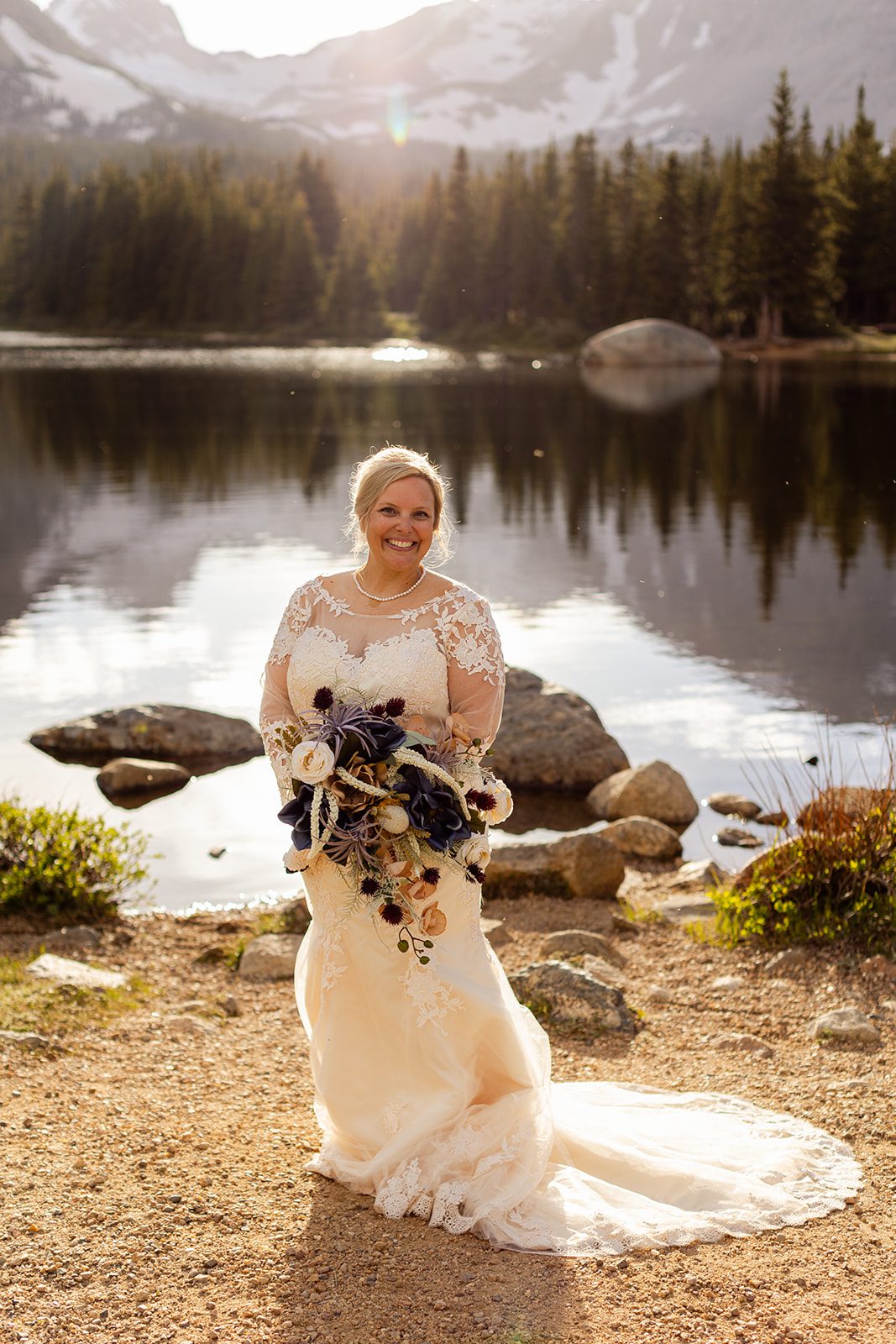 Bride in white gown with flower bouquet at Brainard Lake.