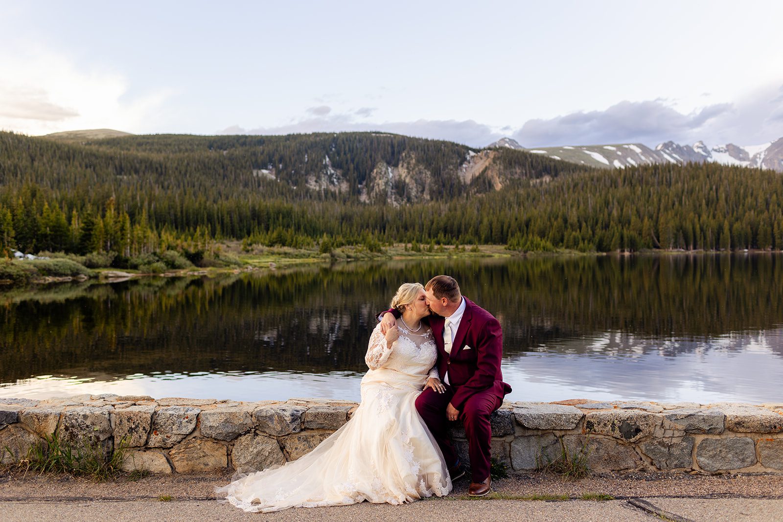 Bride and groom kissing next the gorgeous alpine lake.