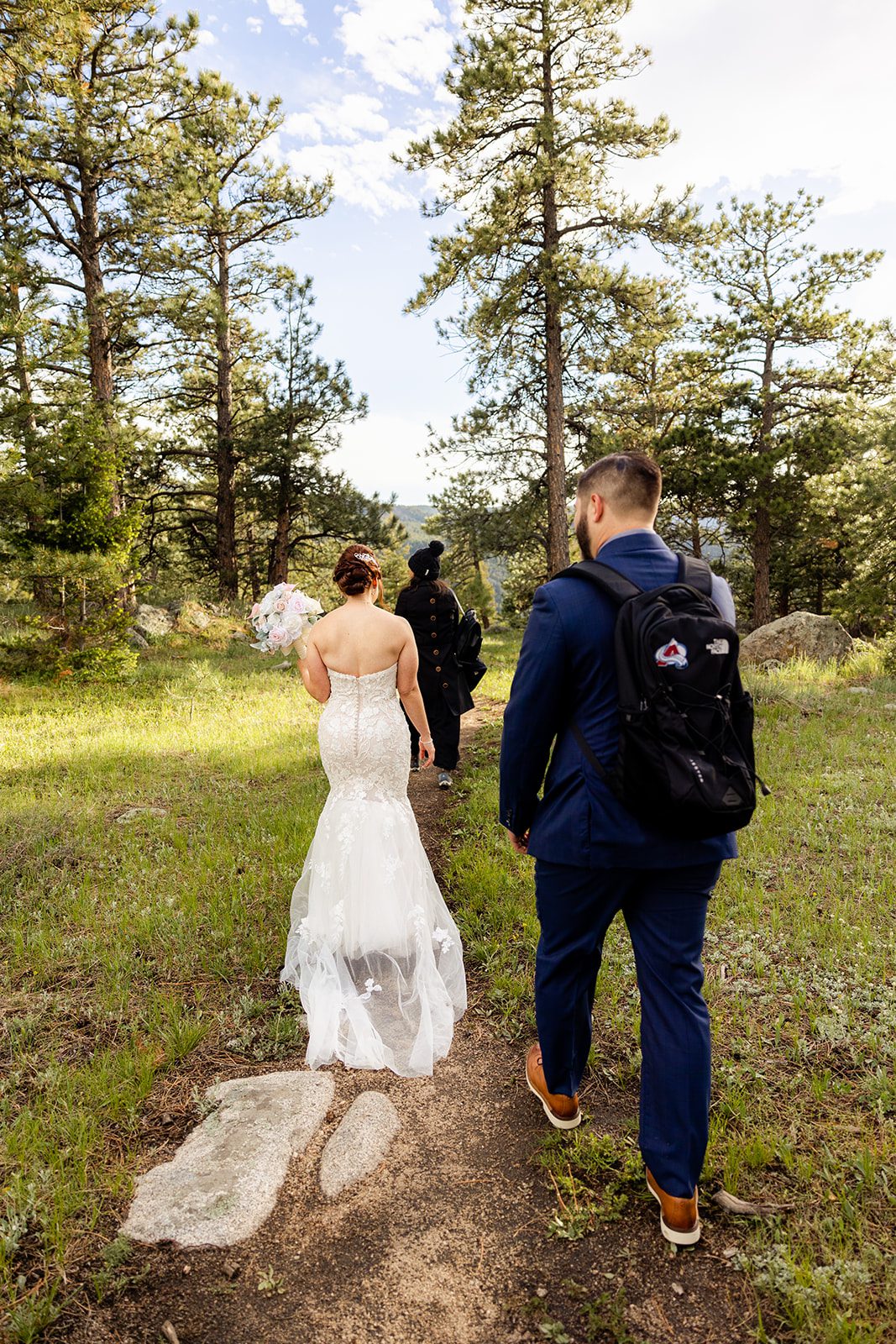 bride and groom walk with officiate towards their ceremony for their Boulder elopement with videography.