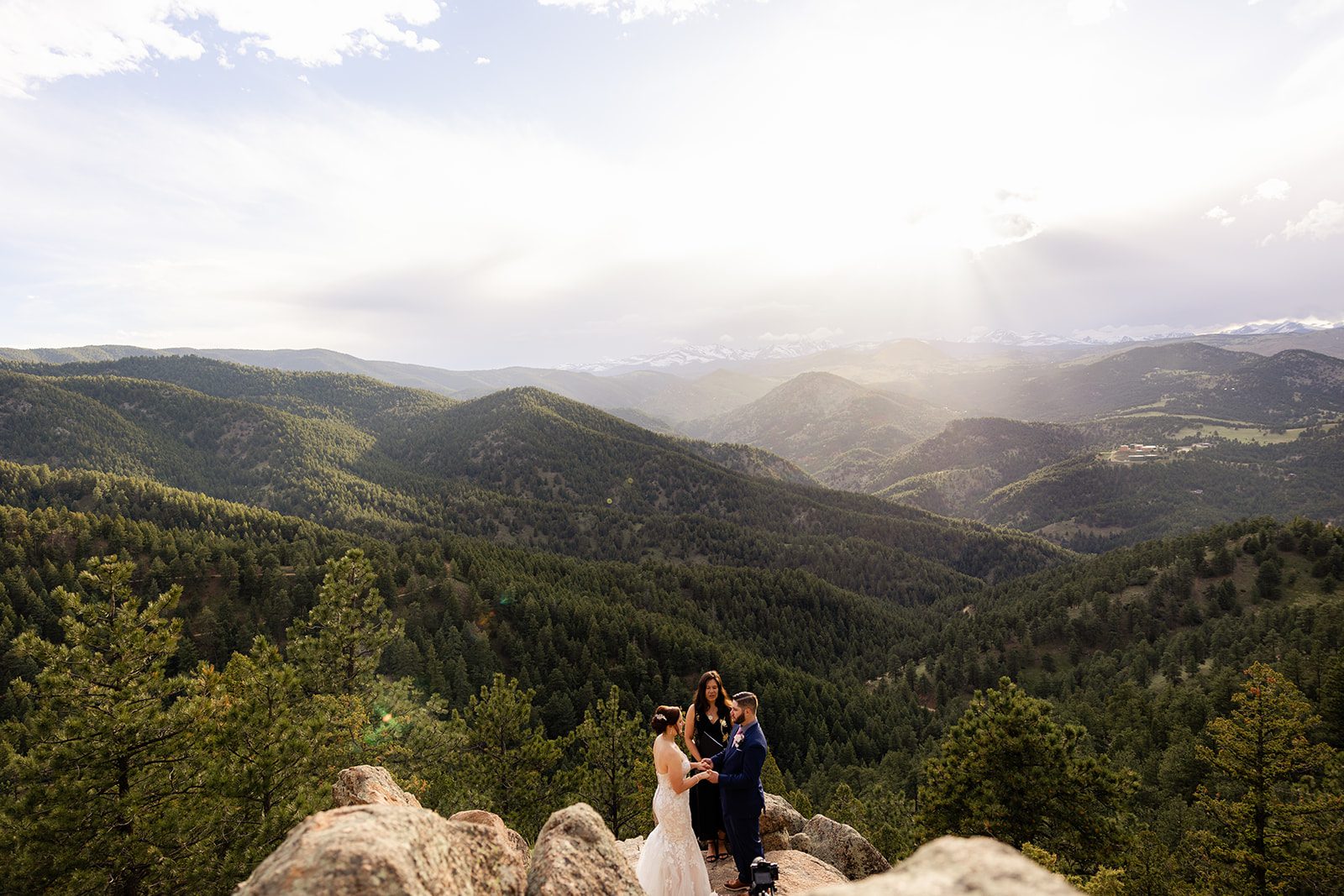a far away shot of the bride and groom during their ceremony with the rocky mountains behind them at  their Boulder elopement with videography.