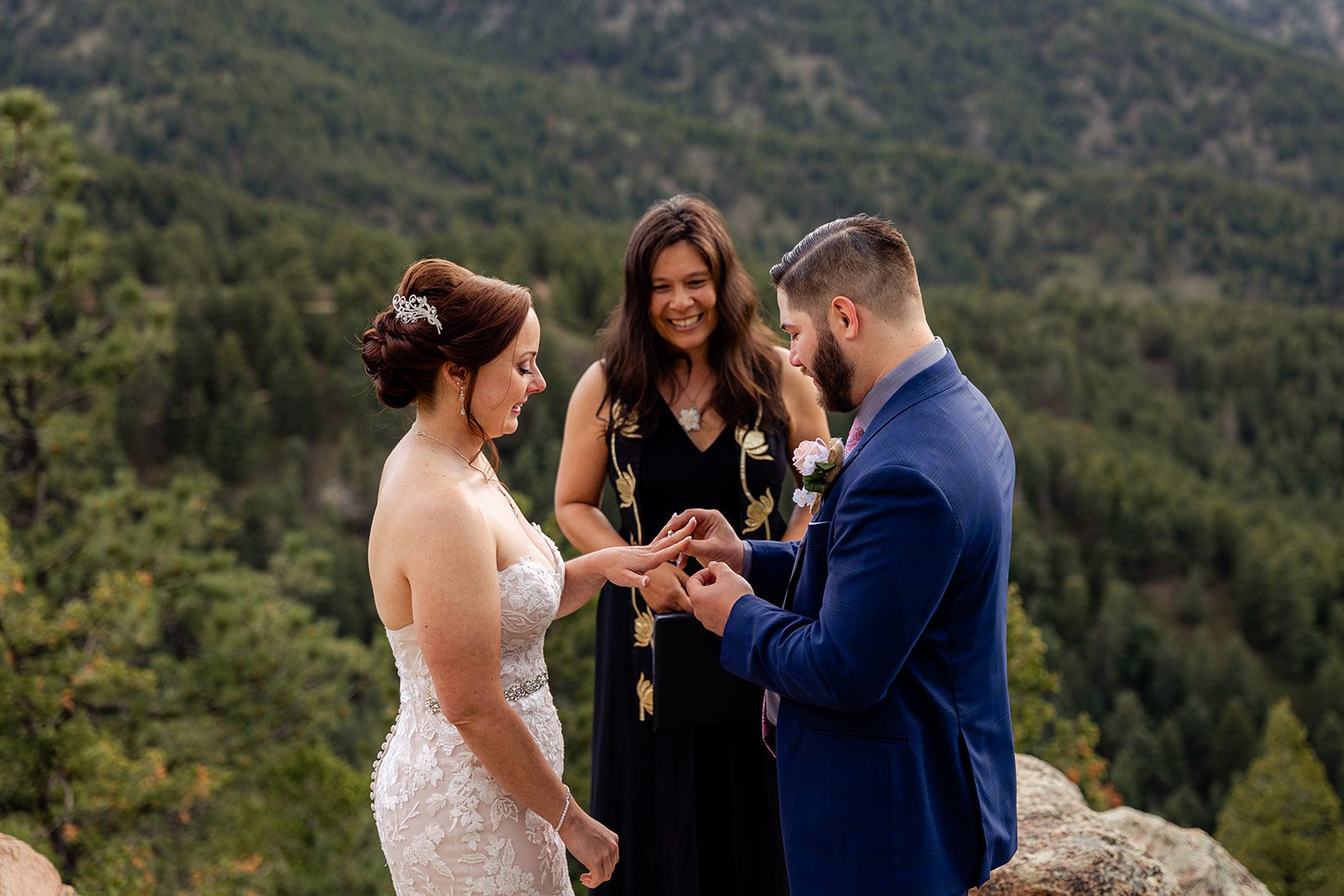 Groom puts the ring on his brides hand during their ceremony at  their Boulder elopement with videography.