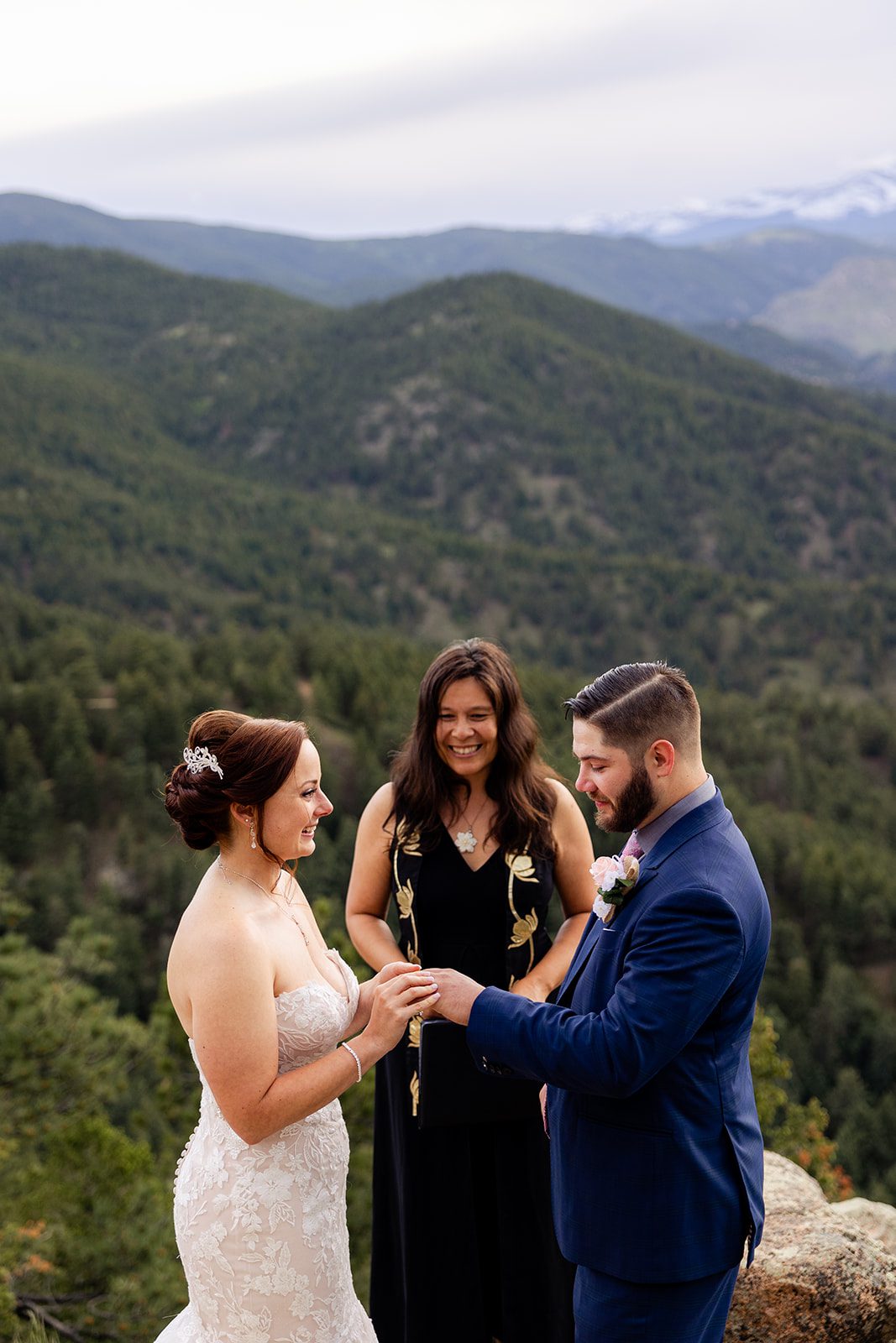 Bride puts the ring on her grooms hand during their ceremony at their Boulder elopement with videography.