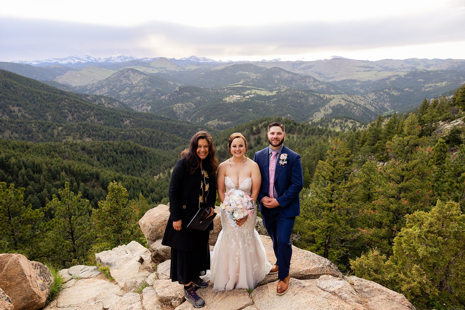 bride and groom pose with their officiant at their Boulder elopement with videography.