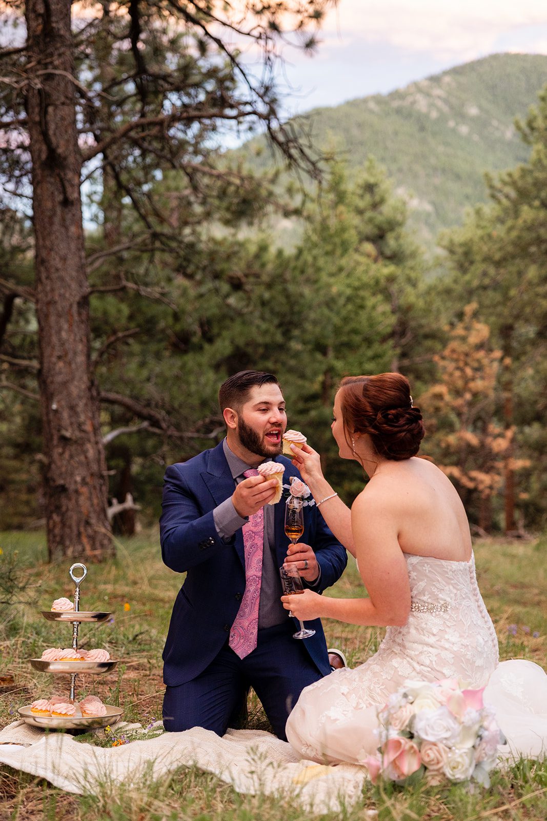 Bride and groom feeding each other cupcakes during their picnic at  their Boulder elopement with videography.