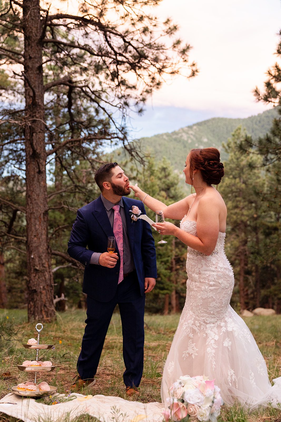 Groom licks icing off his bride's finger during their Boulder elopement with videography.