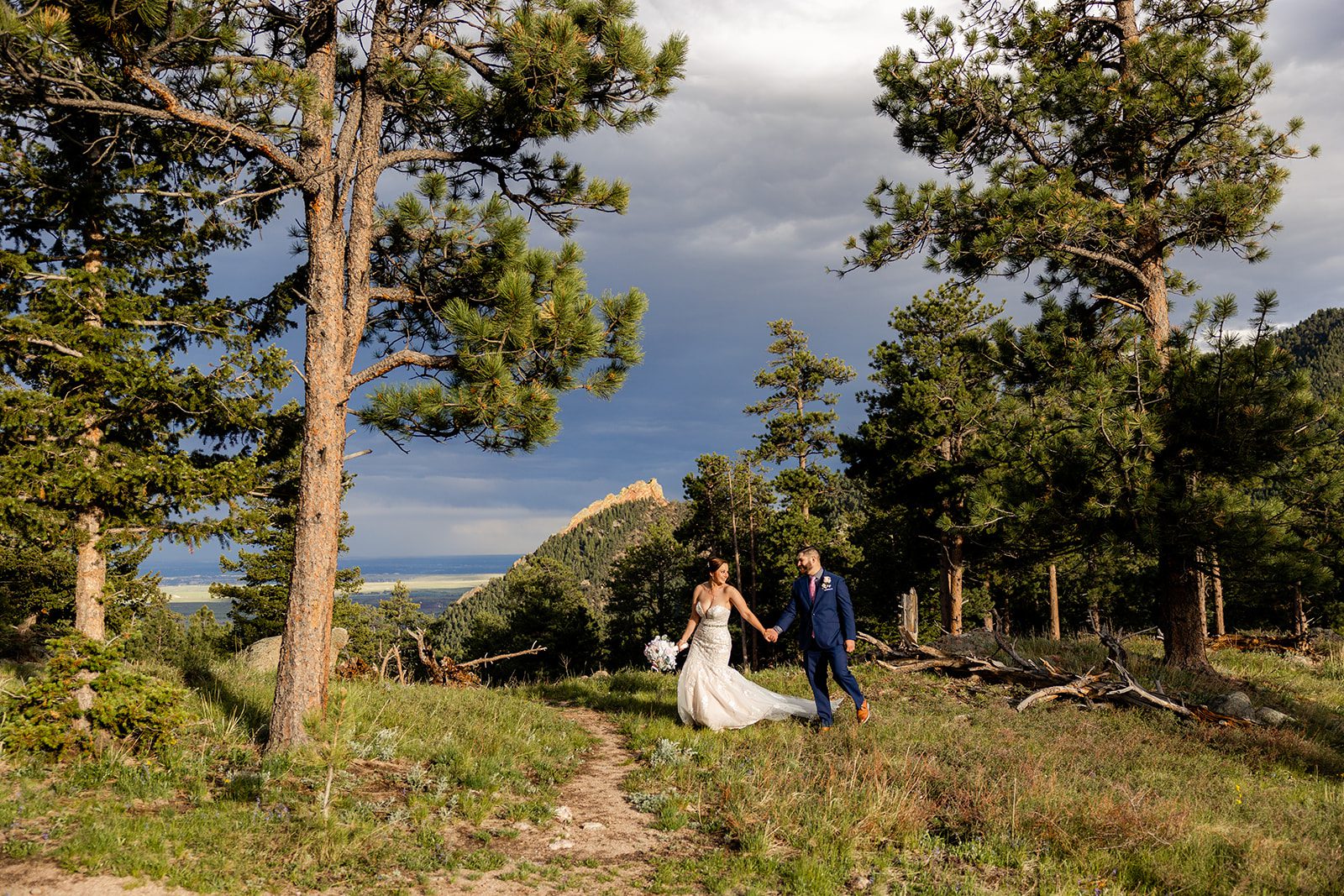 bride and groom walking hand in hand on Flagstaff Mountain during  their Boulder elopement with videography.