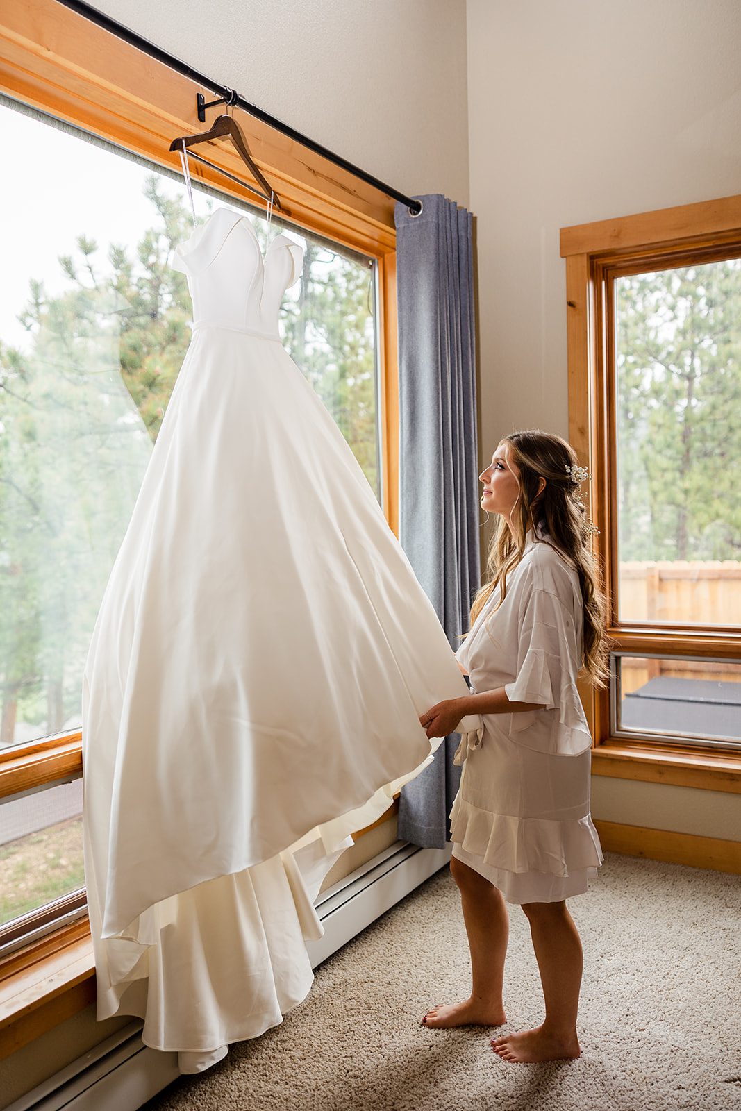 The bride looking at her gown while getting ready at the airbnb before her Hidden Valley Elopement. 