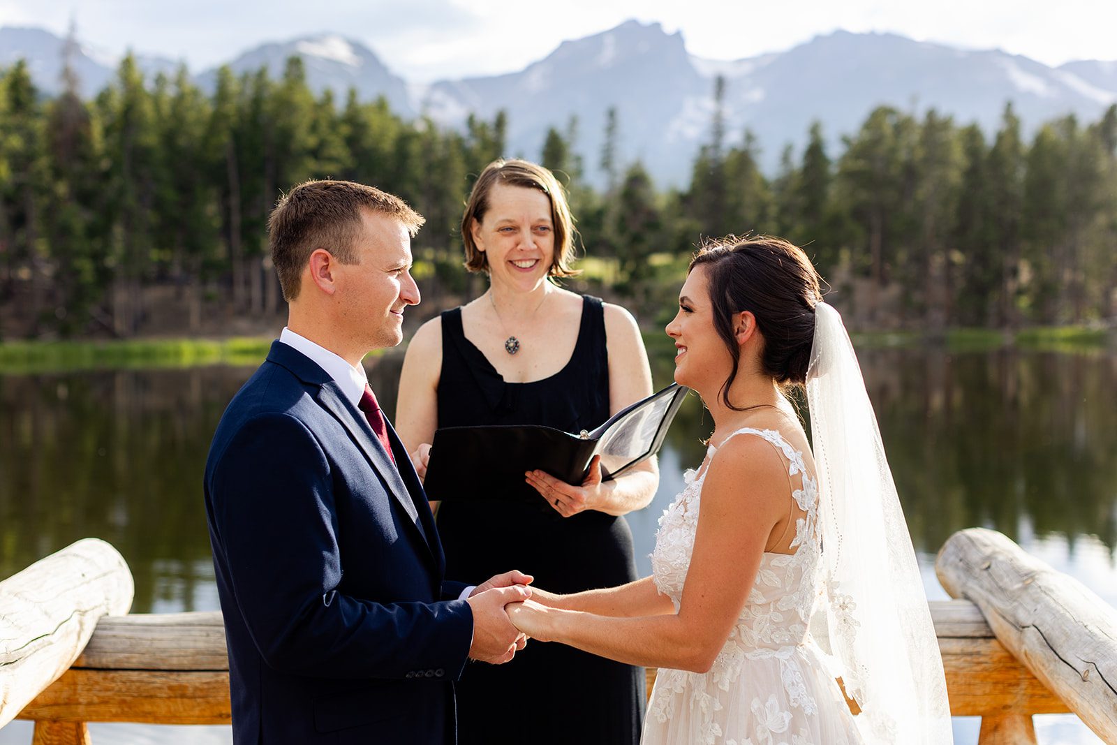 Bride and groom with officiant at Sprague Lake during summer elopement ceremony