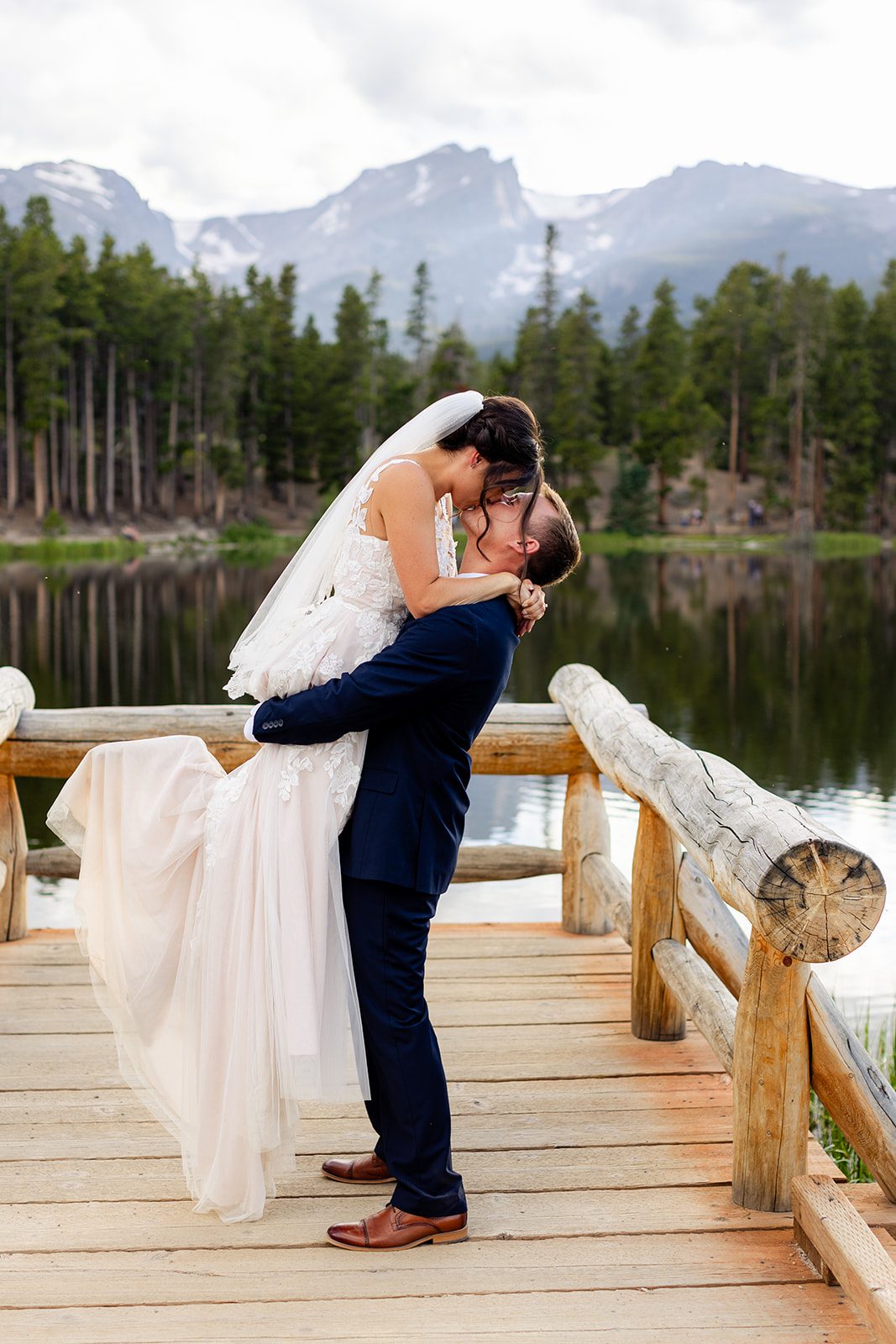 Groom lifts his bride up on Sprague Lake dock after their Summer elopement ceremony