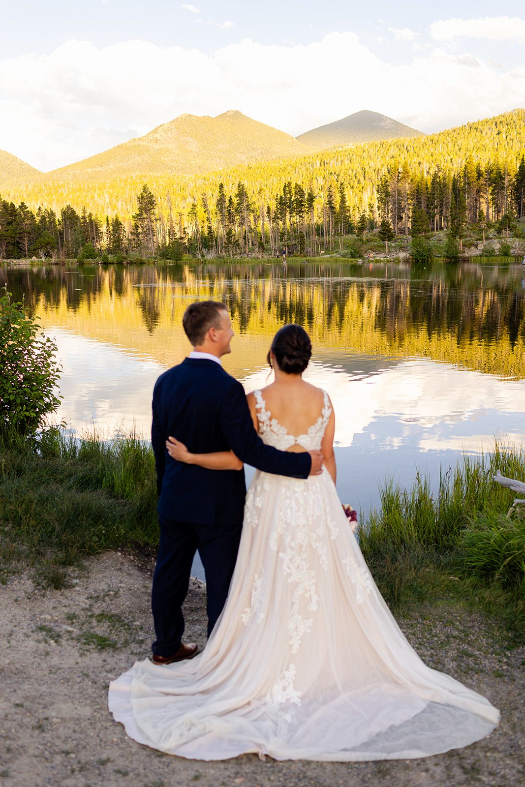 Bride and groom looking out at Sprague Lake at sunset after their elopement ceremony