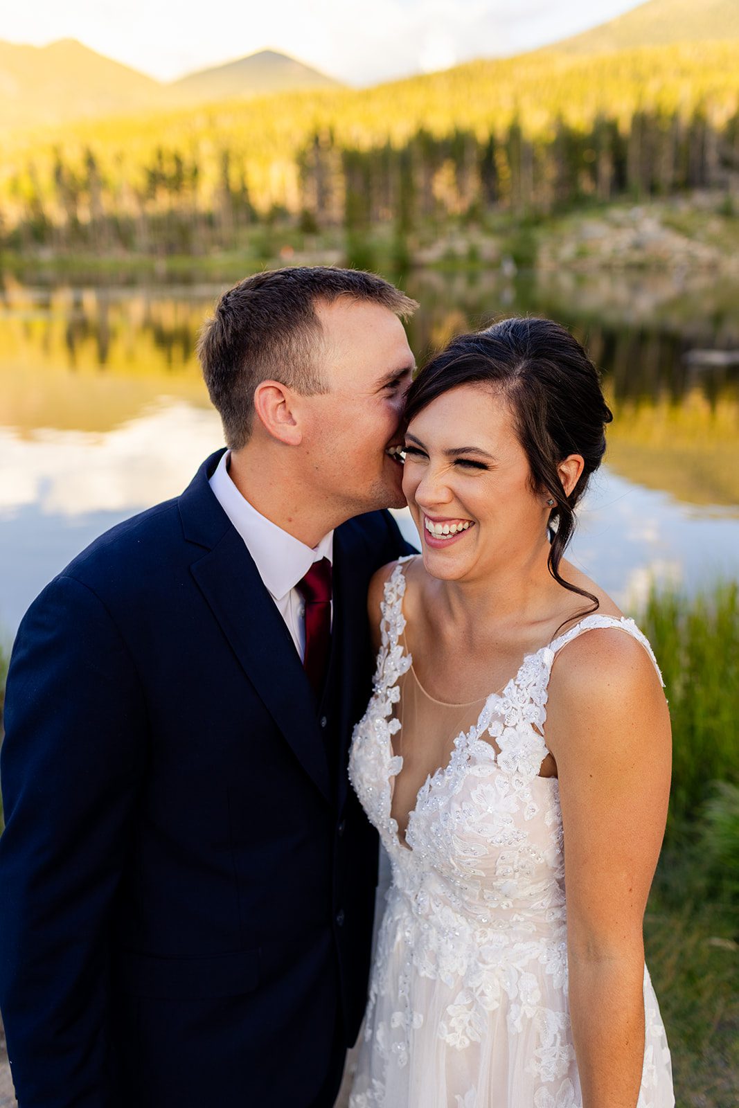 groom kisses his bride in front of Sprague Lake