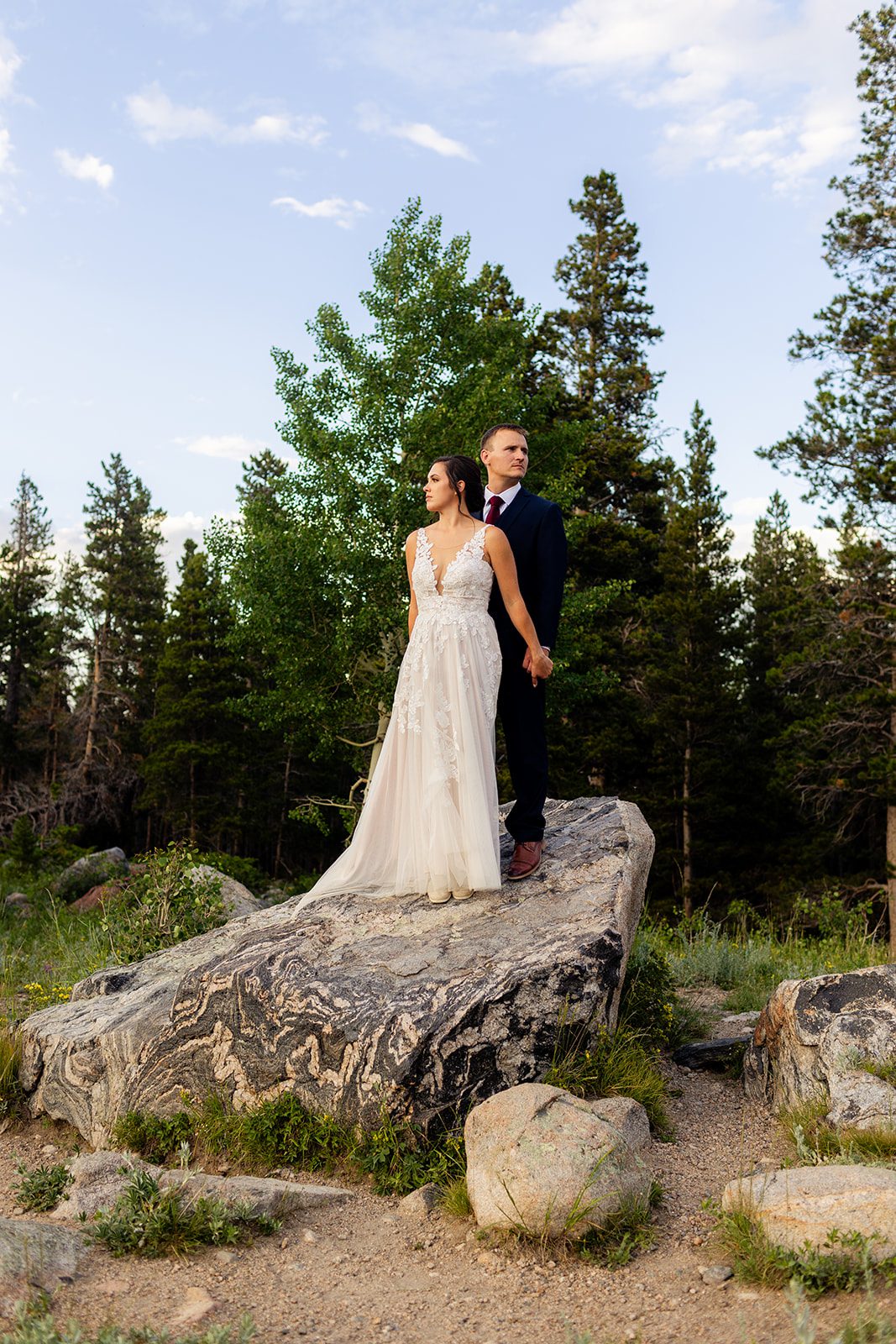 Bride and groom standing on a boulder after Sprague lake elopement ceremony