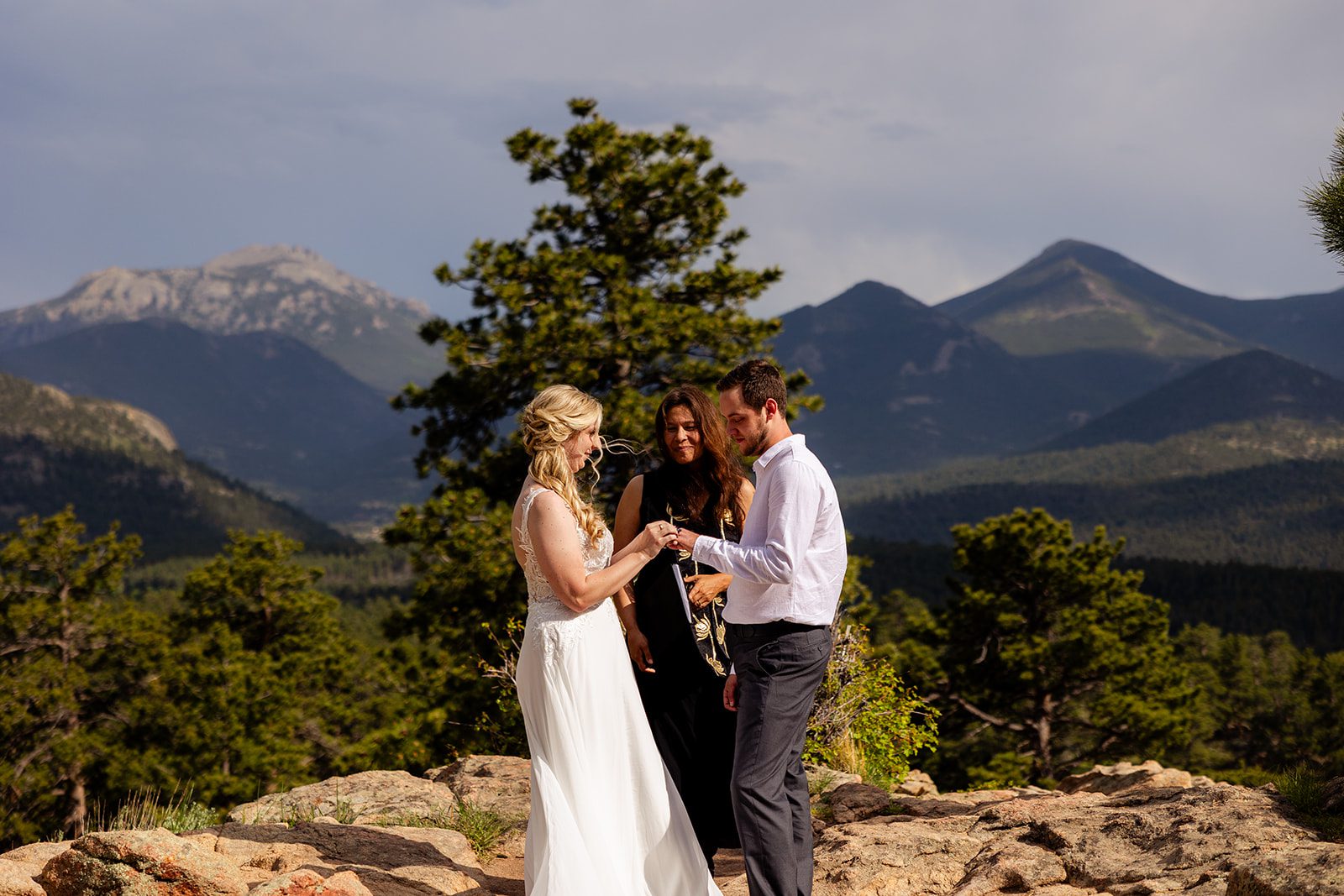 bride putting ring on her groom's hand during Summer Elopement at 3M Curve in rocky mountain national park.