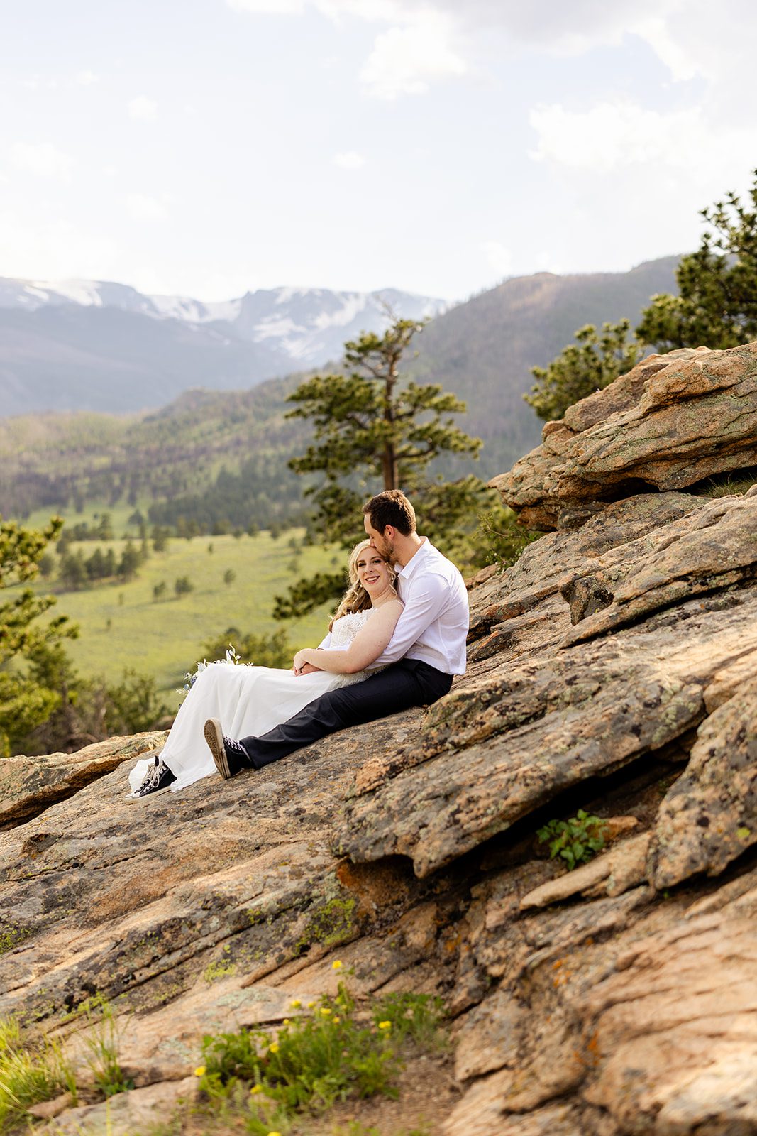 bride and groom sitting on a rock after their summer elopement