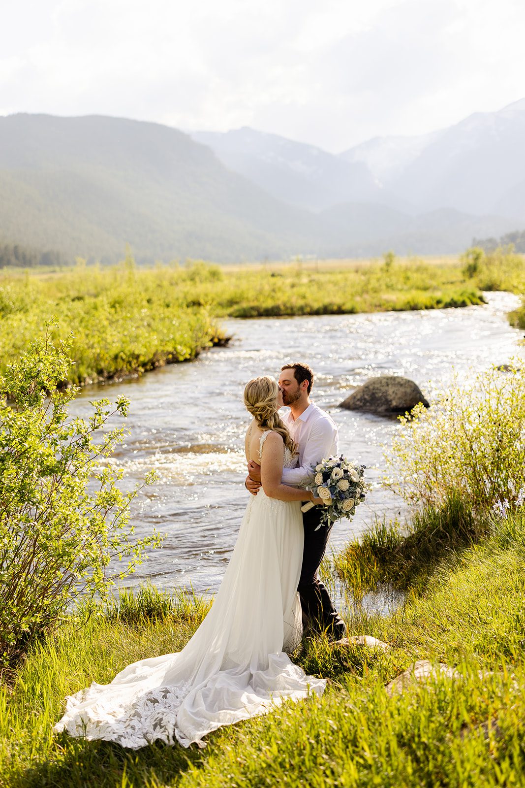 bride and groom kissing near mountain lake in 3m curve after ther summer elopement ceremony.