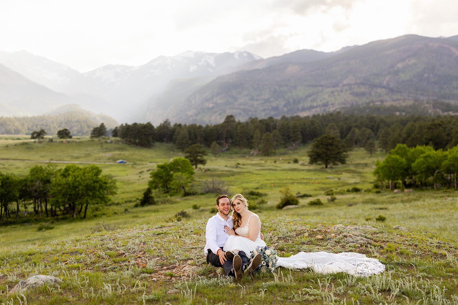 bride and groom sitting in field in rocky mountain national park after 3m curve elopement.