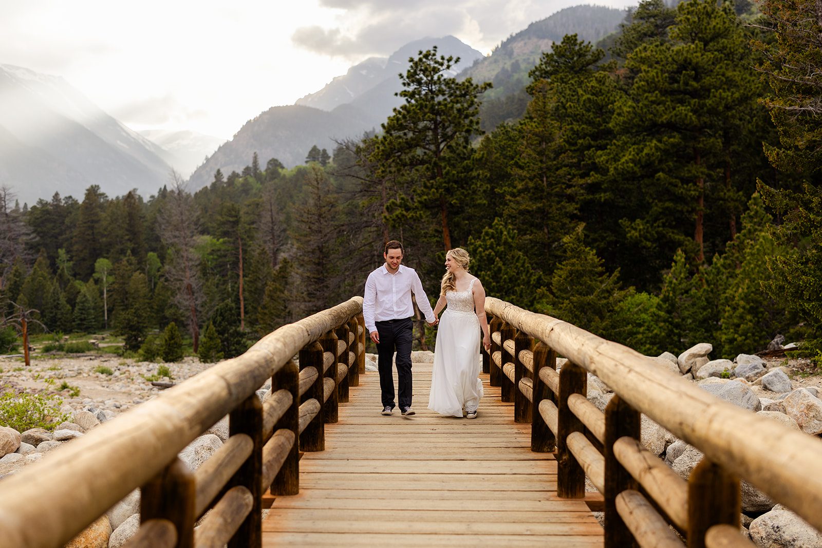 bride and groom holding hands, walking across the alluvial Fan Bridge 
