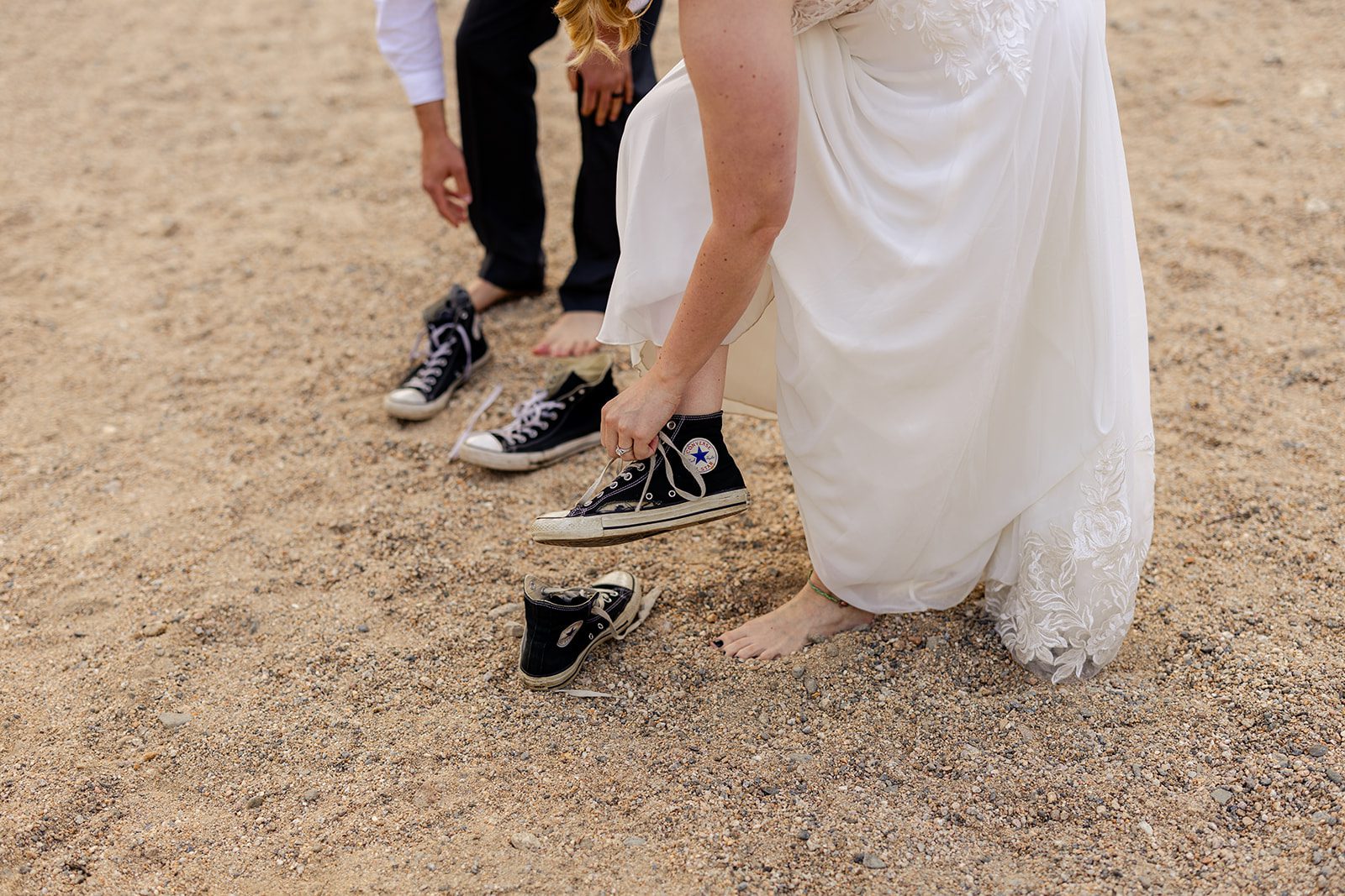 bride and groom taking of their converse shoes to get in the water at the alluvial Fan Bridge & Waterfall after their summer elopement at 3m curve. 