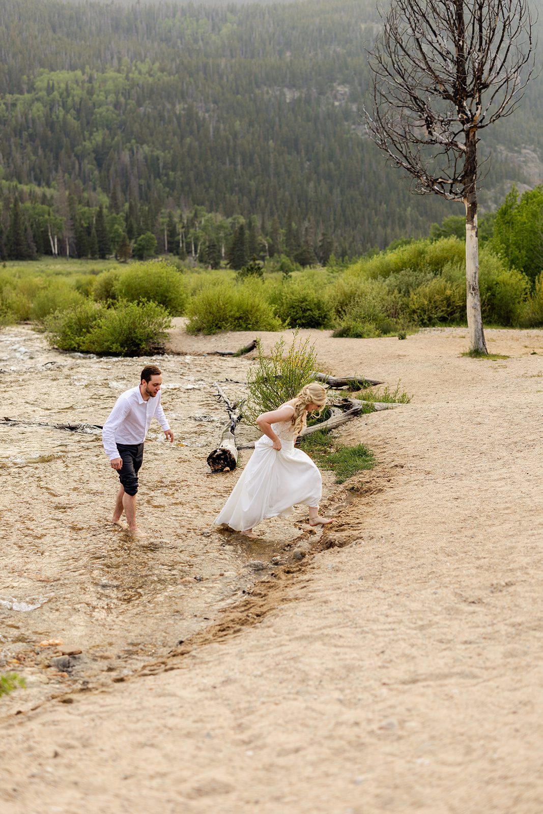 bride and groom walking out of water at alluvial Fan Bridge & Waterfall