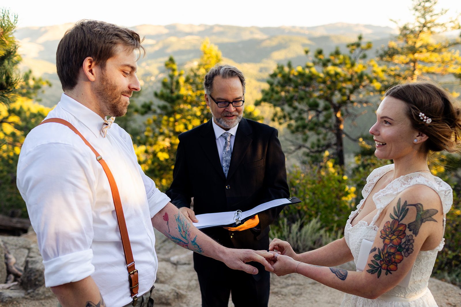 Bride slides ring on grooms hand at Artist Point for their sunrise elopement ceremony