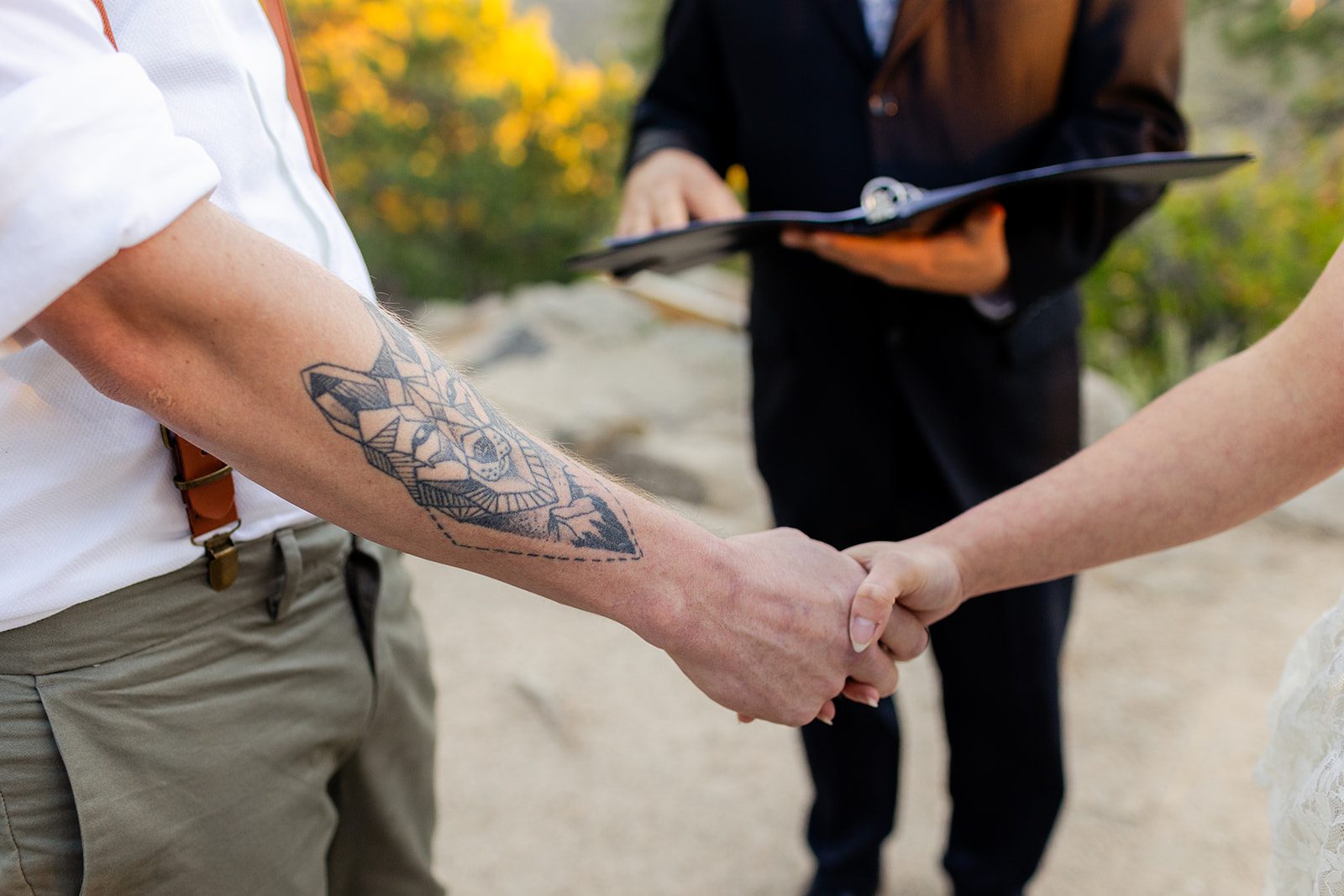 tattooed groom and bride holding hands in Colorado during elopement ceremony