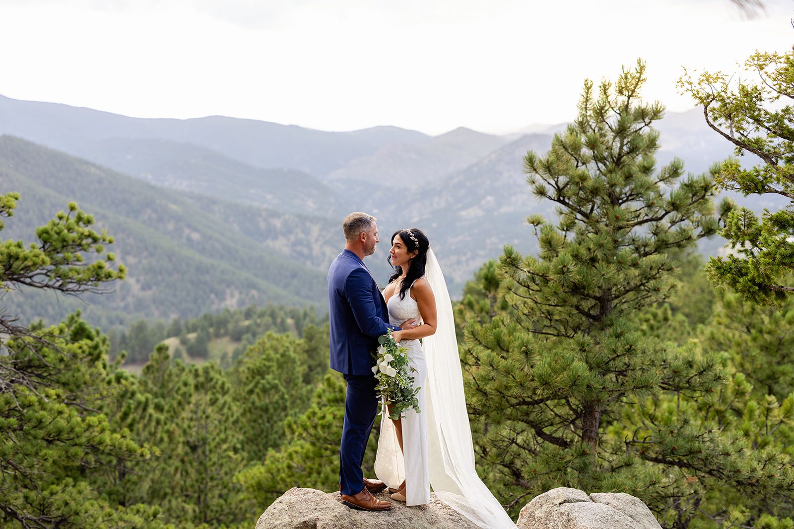 bride and groom looking at each other with views of the rockies in the distance after their elopement. 