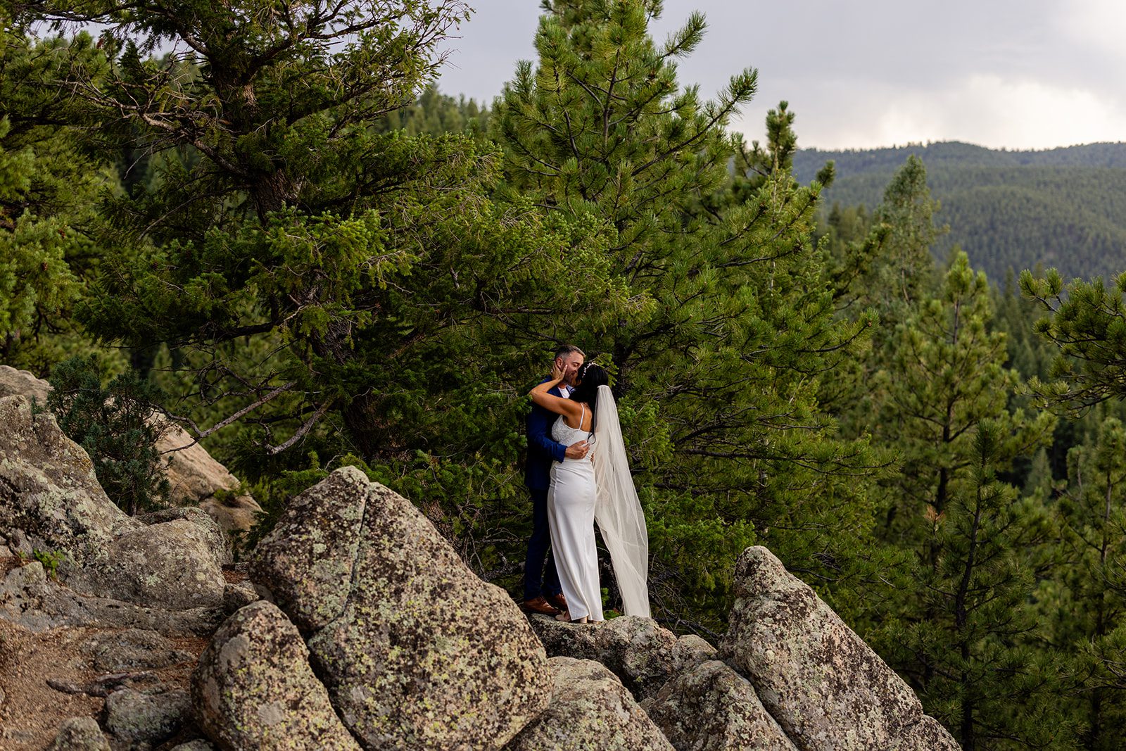 bride and groom on bluff near boulder in colorado 