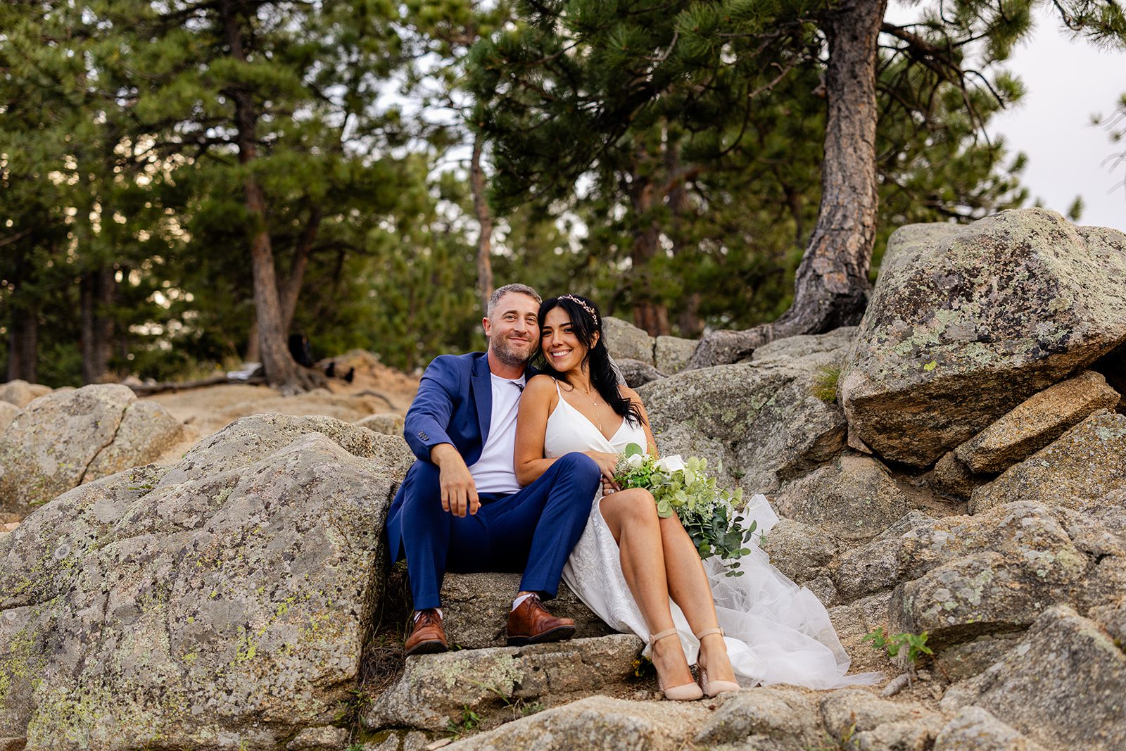 bride and groom sitting on boulder after elopement ceremony at artist point. 