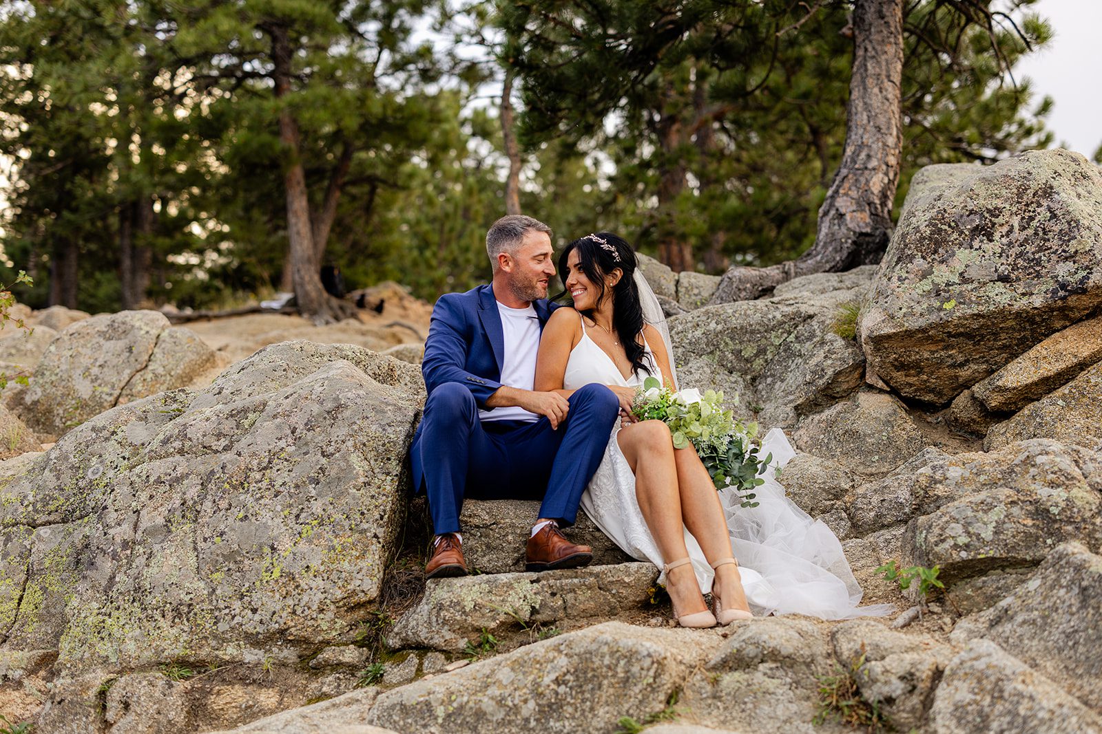 bride and groom sitting on boulder after elopement ceremony 
