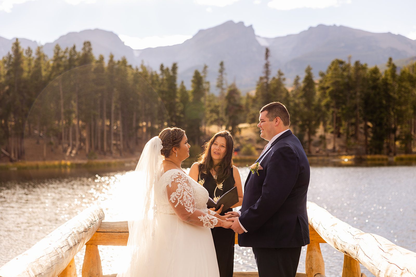 bride and groom holding hands during their Fall elopement ceremony at Sprague Lake in rocky mountain national park. 