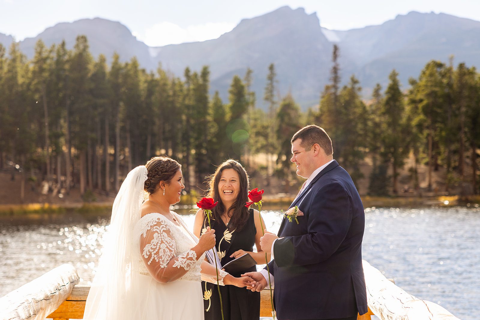 bride and groom holding roses during their Fall elopement ceremony at Sprague Lake. 