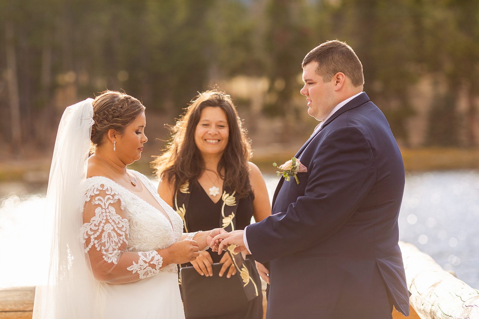 bride slides ring on her grooms finger during Fall elopement at Sprague Lake. 