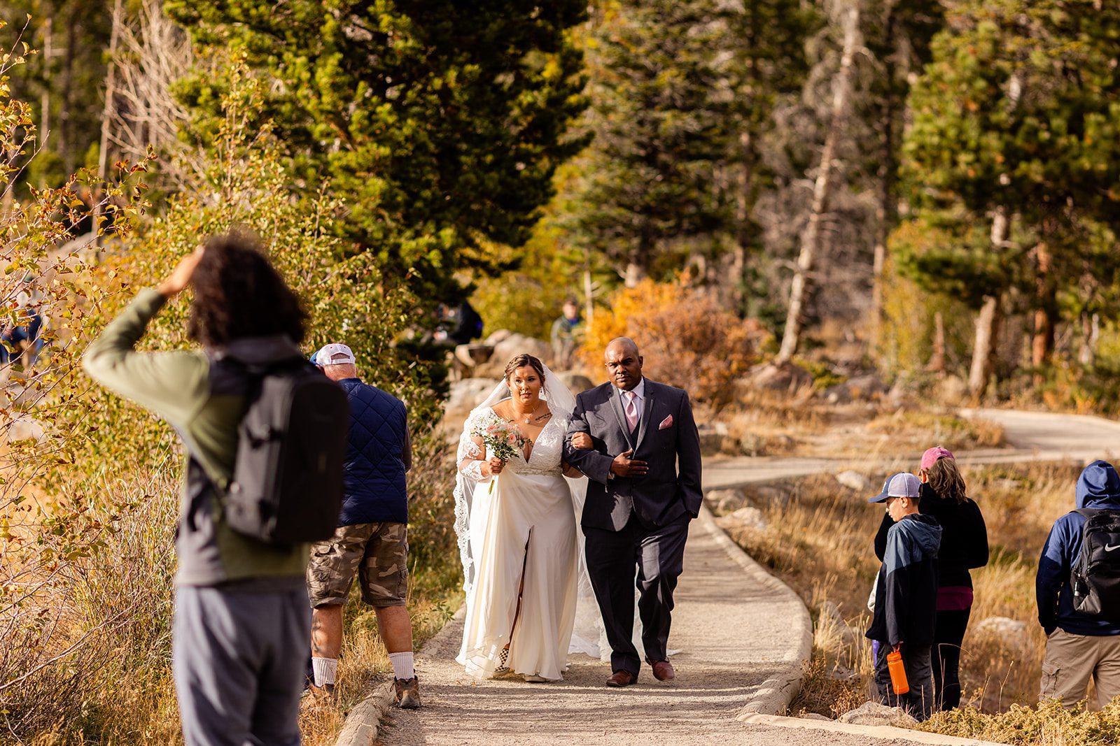 bride walking with her father down the aisle towards her groom for her fall elopement in rocky mountain national park. 