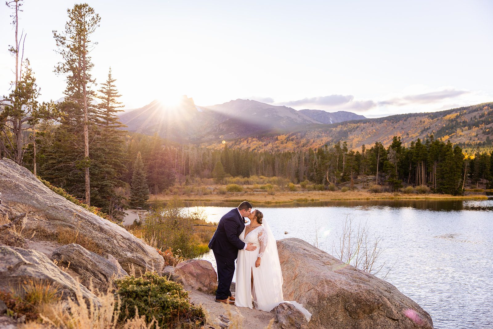 Bride and groom kissing at sunset next to Sprague Lake after their fall elopement. 