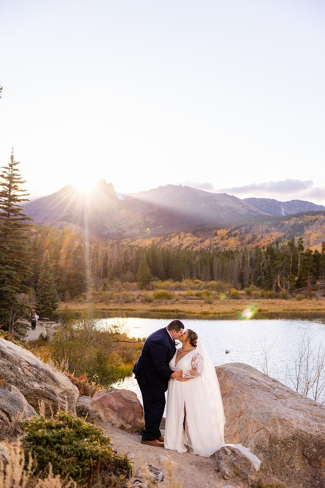 Bride and groom kissing next to Sprague Lake after their fall elopement. 