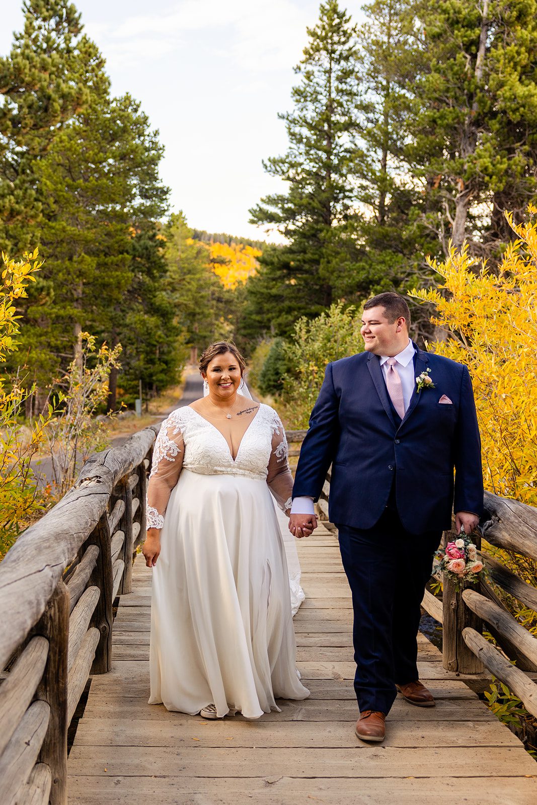 bride and groom walking across bridge during Fall elopement at Sprague Lake