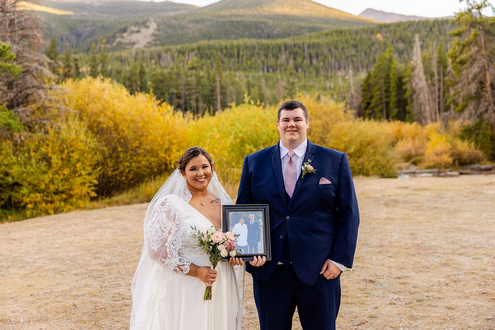 Bride and groom holding family portrait after Fall elopement at Sprague Lake. 