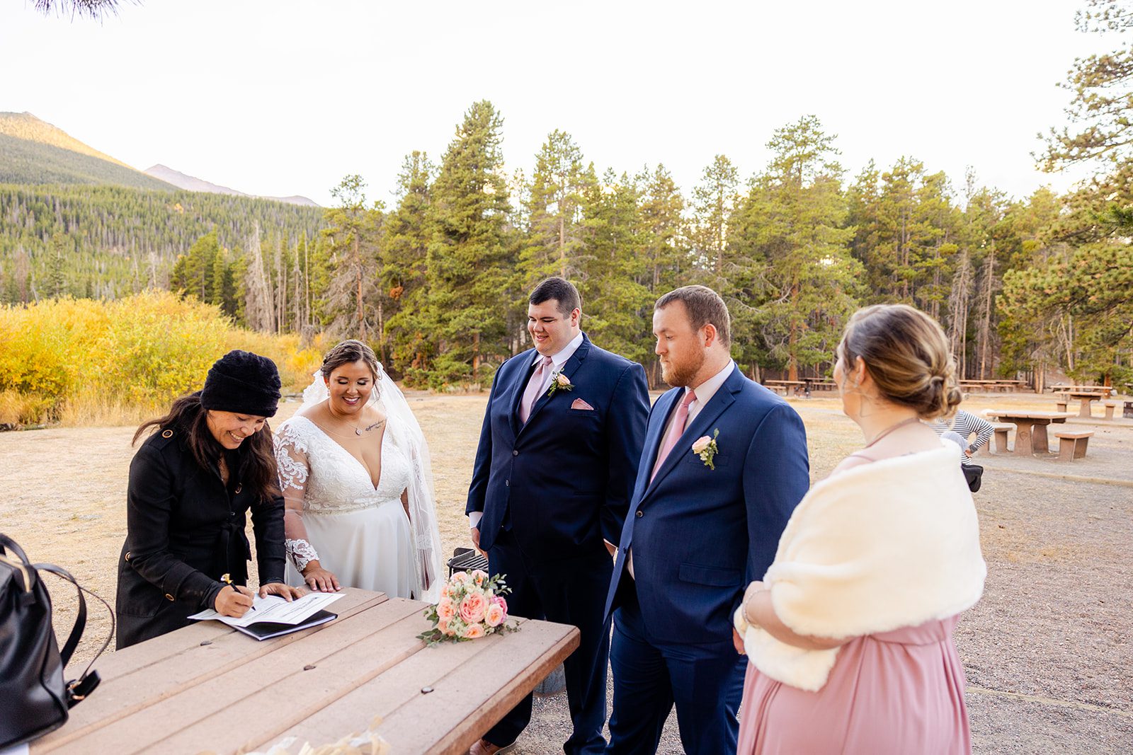 Bride and groom with their officiant and guests during Fall elopement at Sprague Lake. 