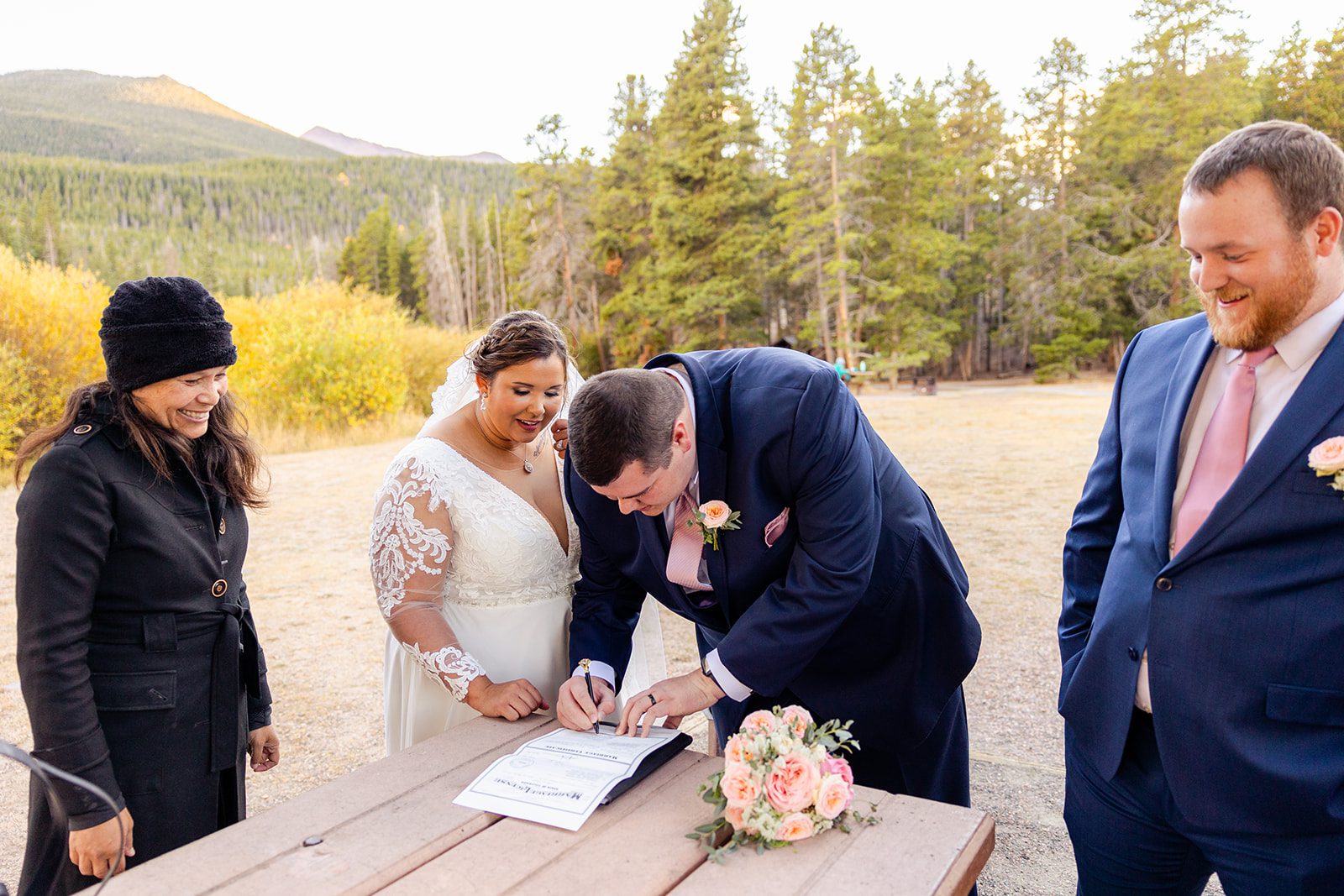 Groom signing his marriage license after their Fall elopement at Sprague Lake in Rocky Mountain National Park. 
